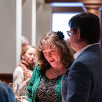 3 guests chat around a standing table